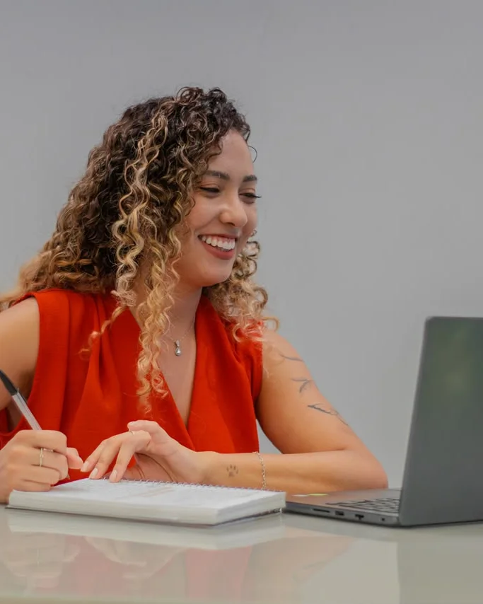 Isabella Lacerda sorrindo em frente ao notebook, durante um atendimento online