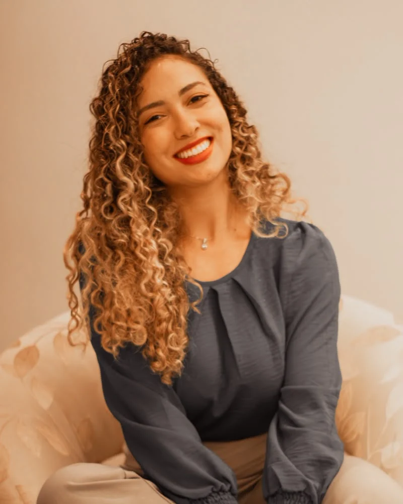 Isabella Lacerda sentada em uma poltrona, sorrindo