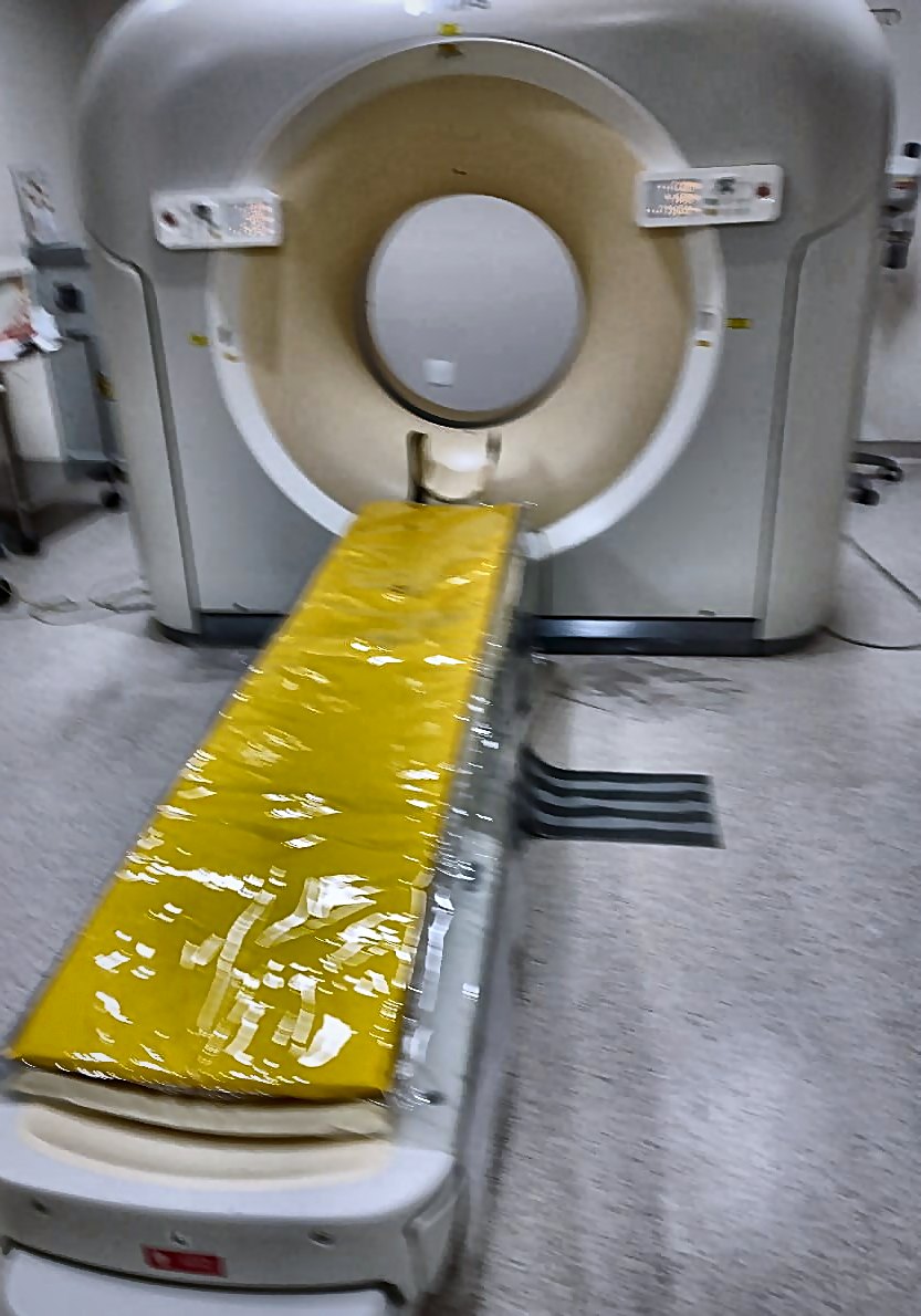 Revestimento amarelo sobre a mesa de um equipamento de tomografia em ambiente hospitalar