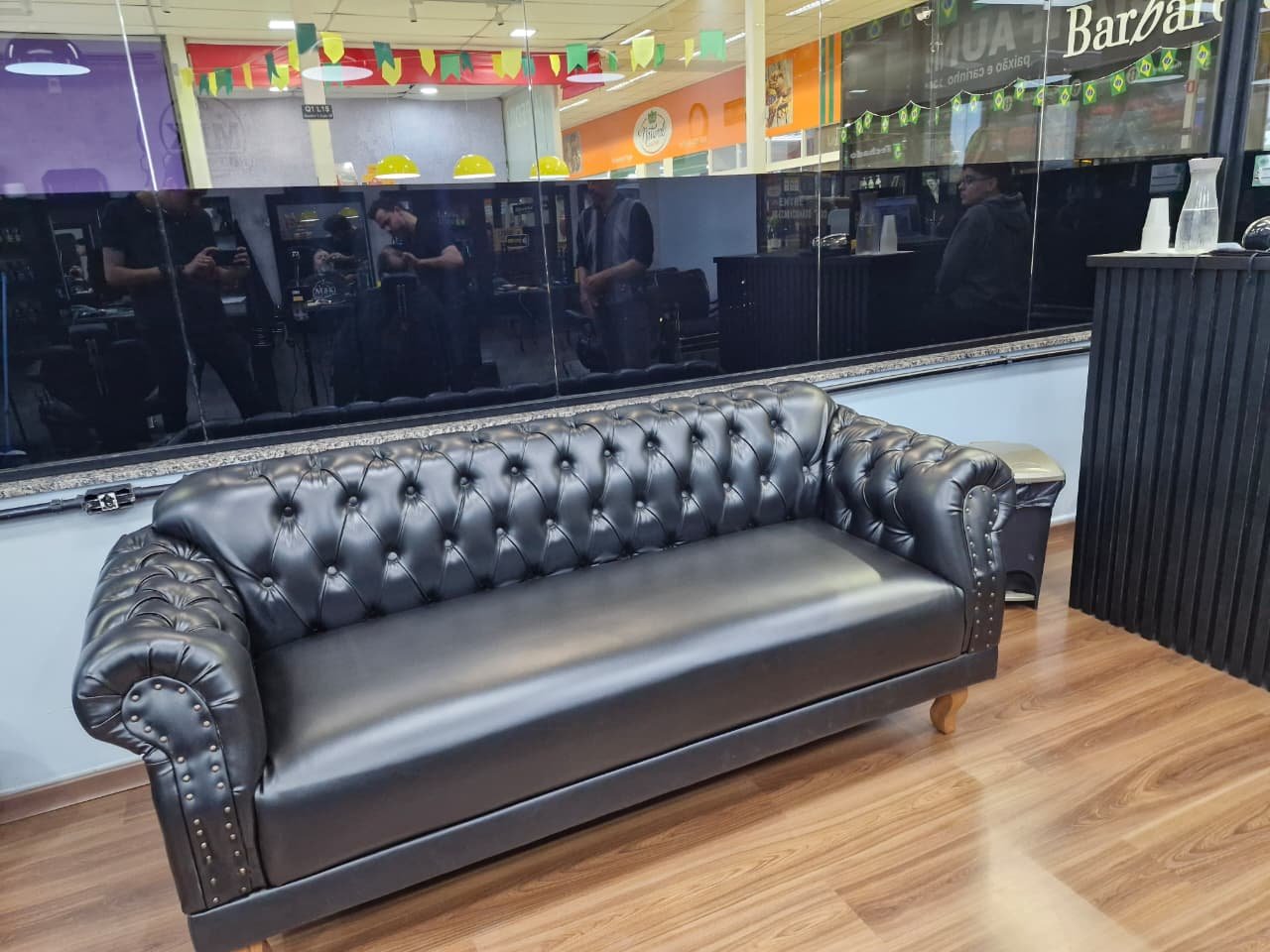 Sofá Chesterfield preto com acabamento capitonê em espaço comercial